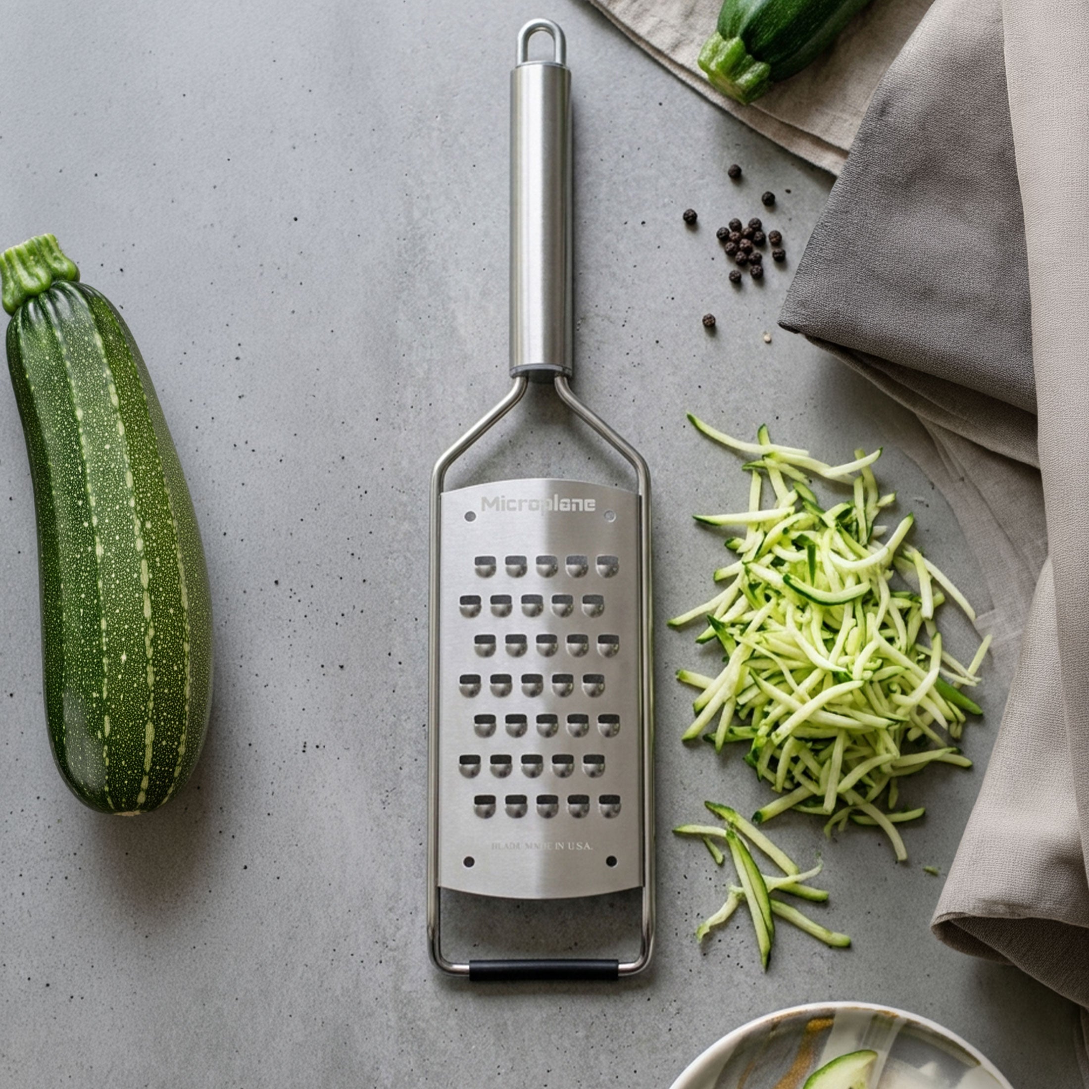 Zester with shredded zucchini on a gray surface