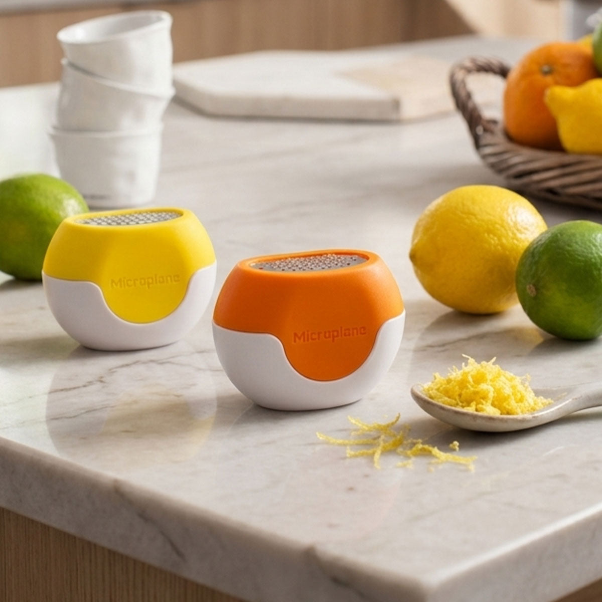 Two Microplane grating devices on a marble countertop with lemons and limes.