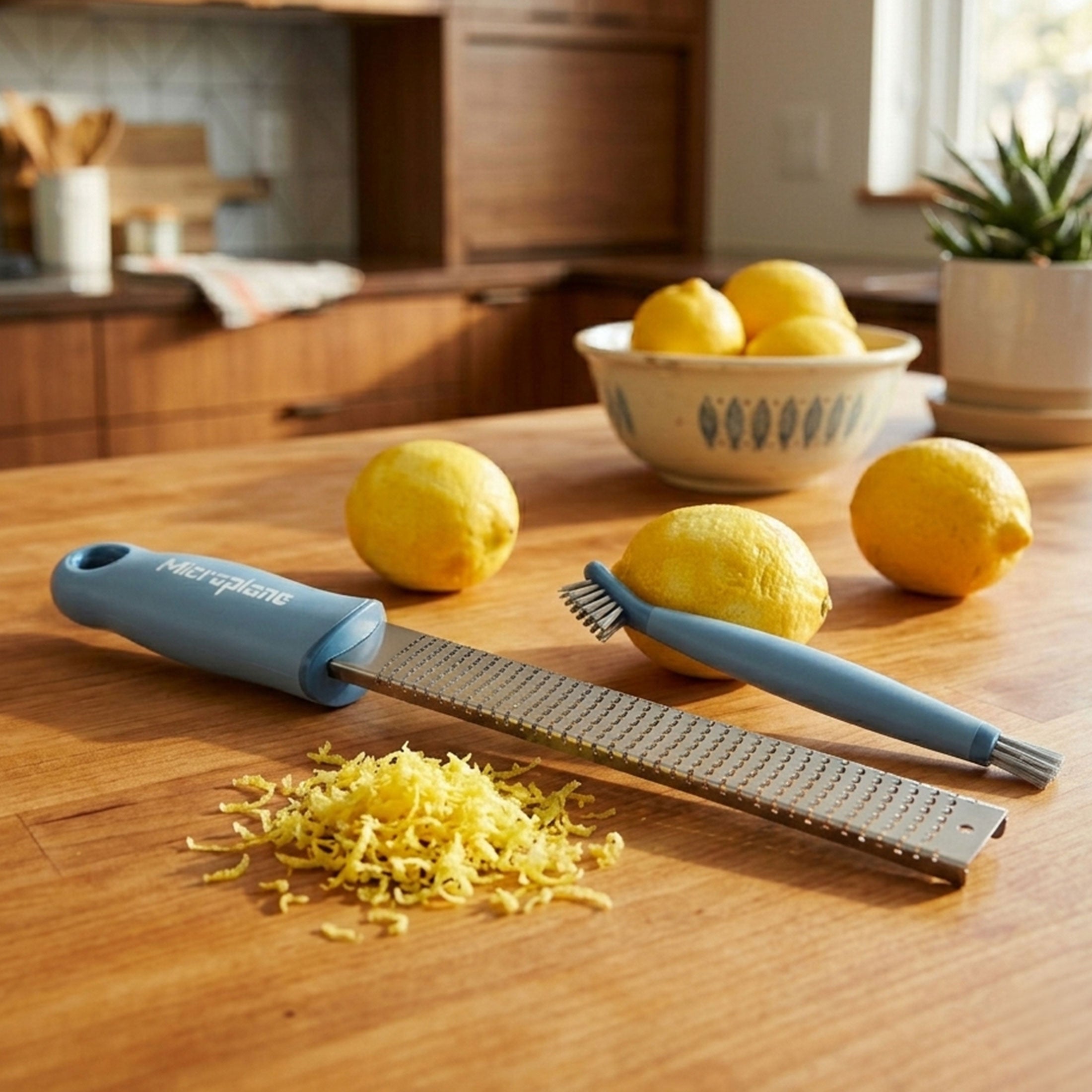 Kitchen scene with a microplane grater, lemons, and a bowl on a wooden countertop.