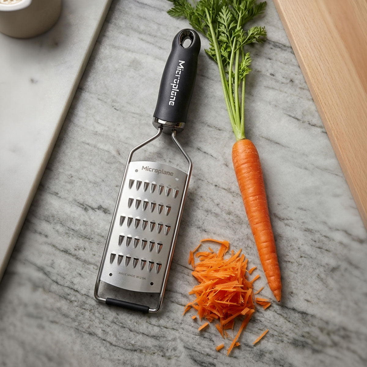 Microplane grater with shredded carrot on a marble surface