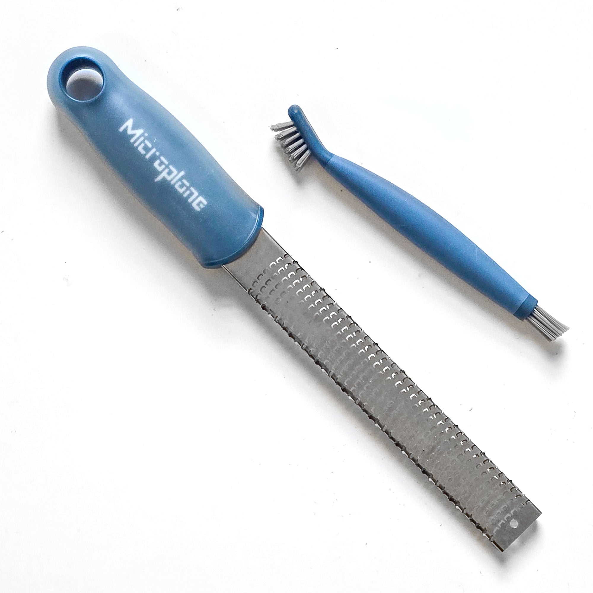 Blue Microplane grater and brush on a white background