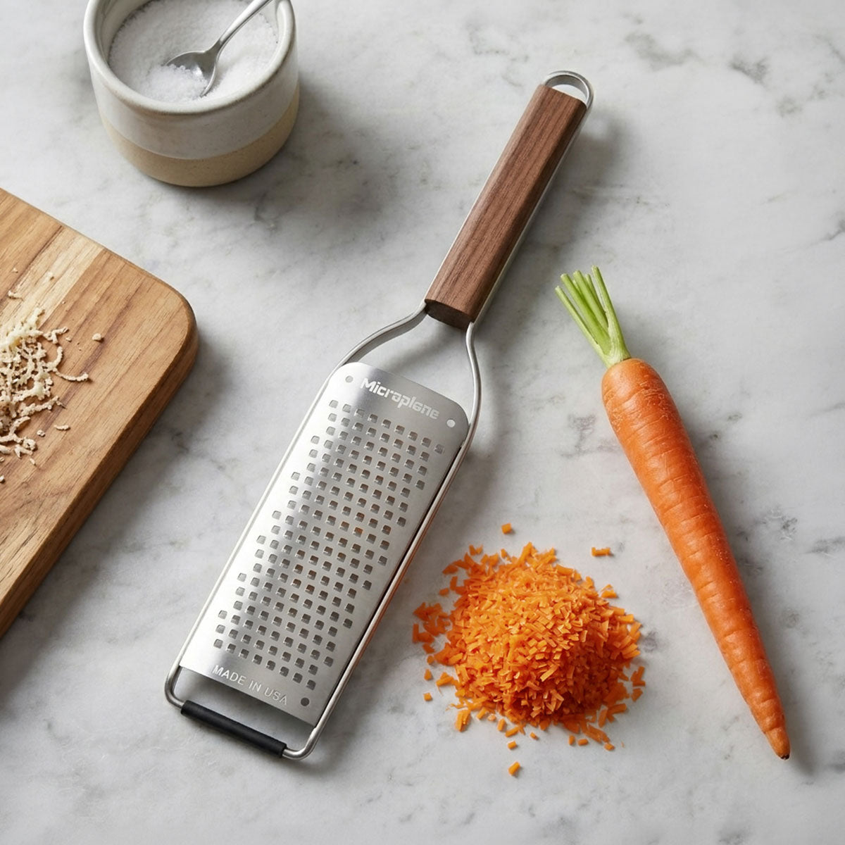 Microplane grater with shredded carrot on a marble surface