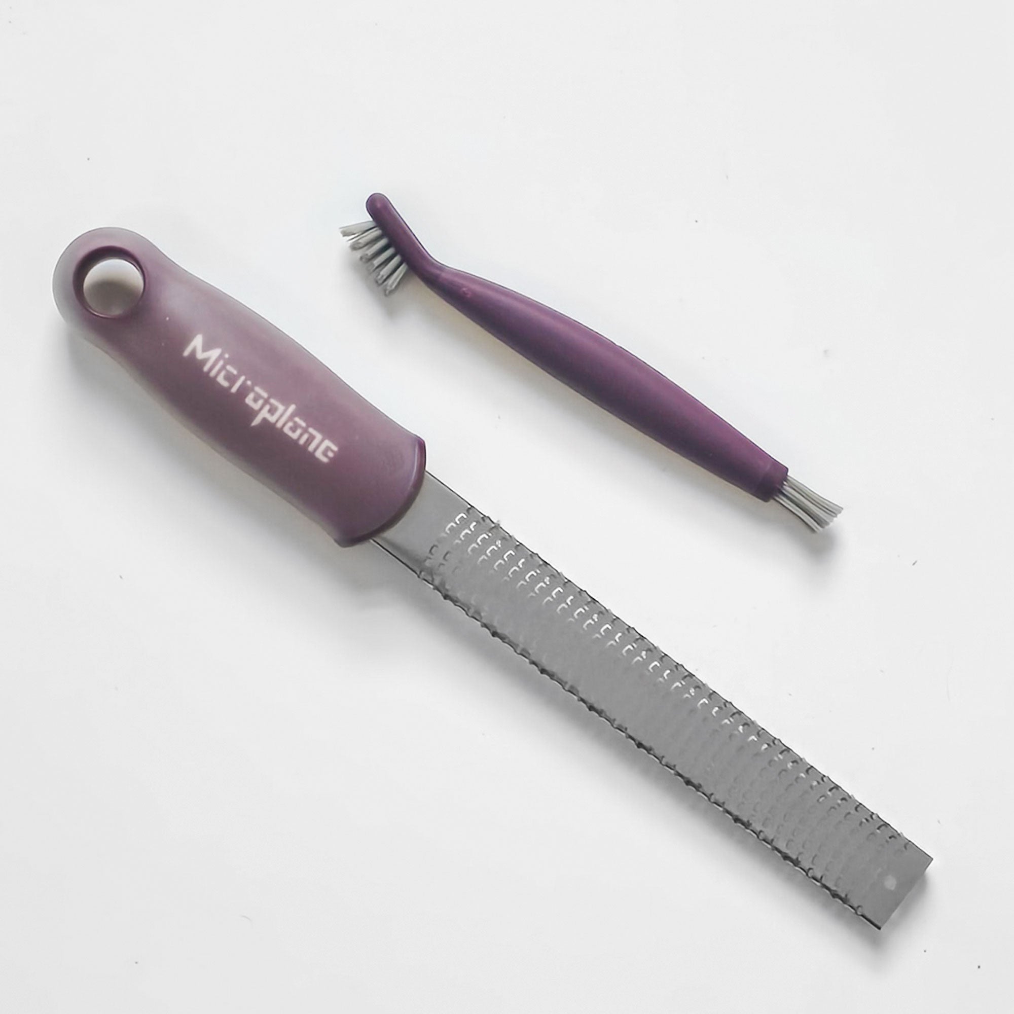 Purple Microplane grater and brush on a white background